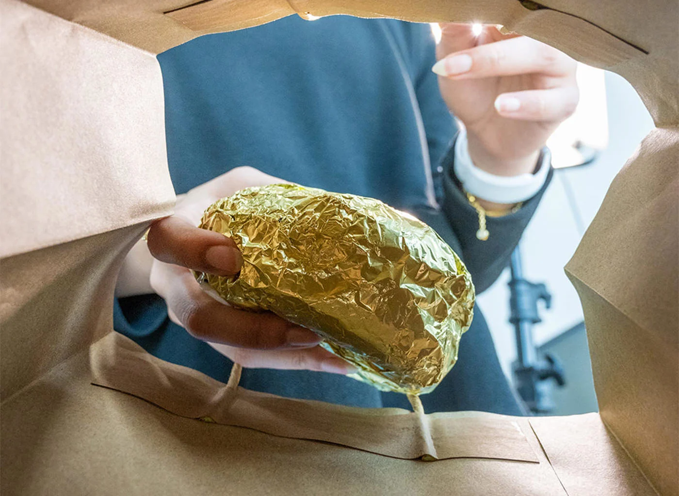 A woman taking a packaged burger out of a bag